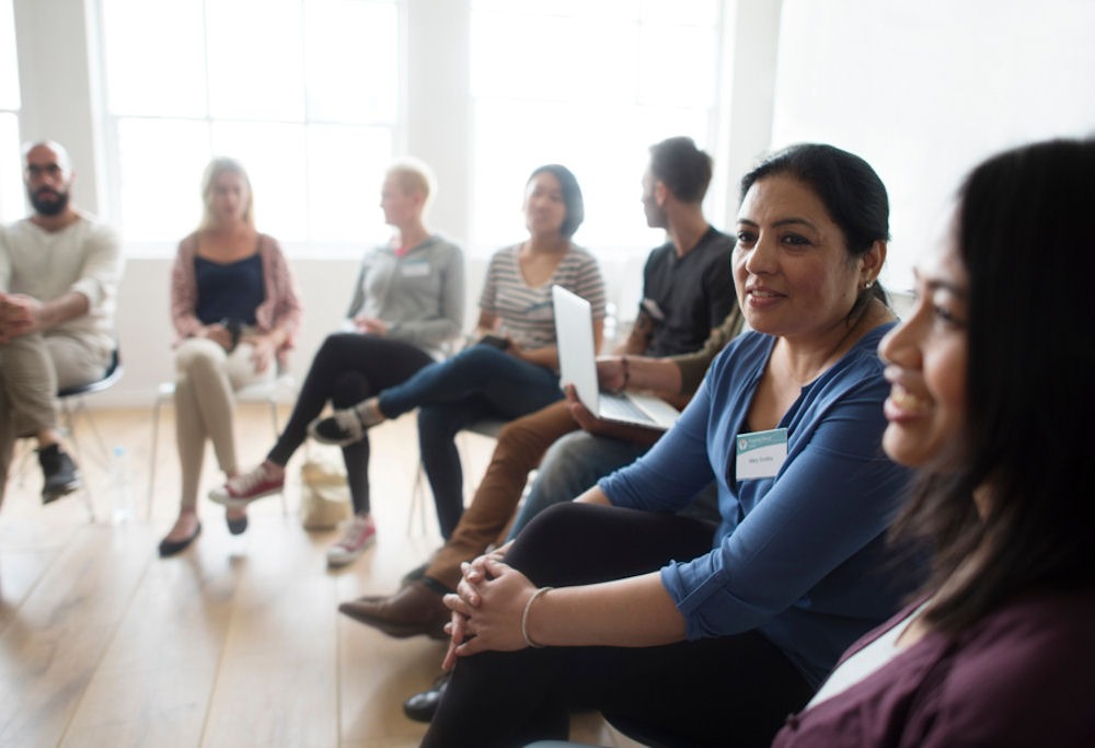 group of diverse individuals sitting in circle for group therapy